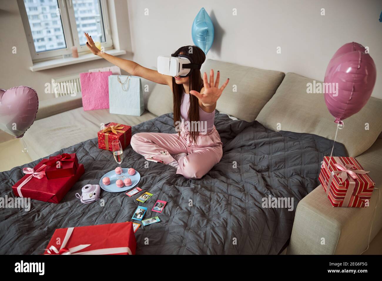 Femme dans des lunettes VR assis à pieds croisés sur le lit Banque D'Images