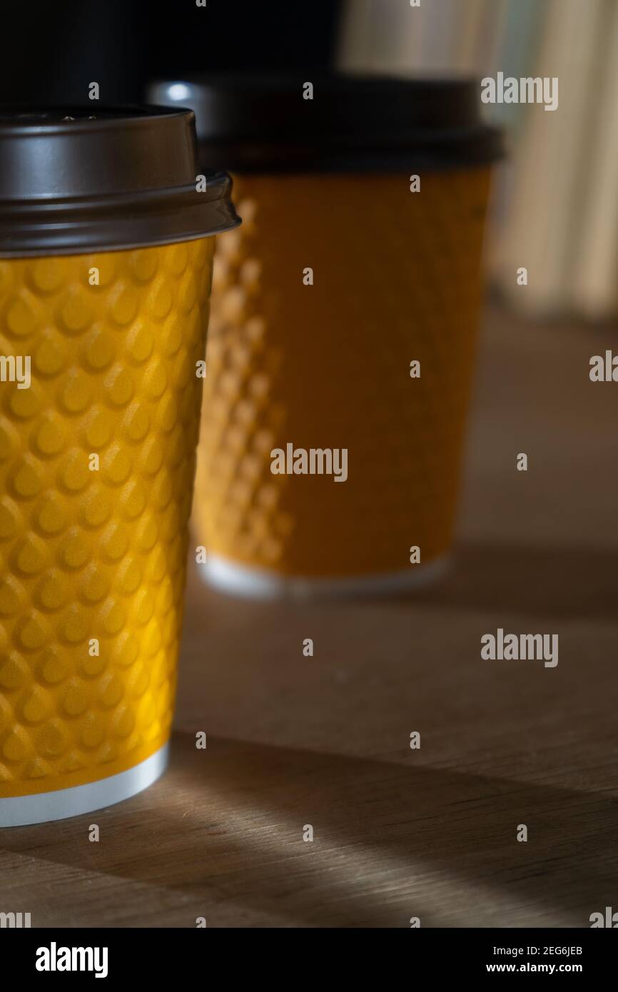 Gobelet en papier côtelé jaune avec couvercle en plastique pour les boissons à emporter dans les restaurants fast-food. Une tasse de café, cacao, thé d'un café de rue. Place pour vous Banque D'Images