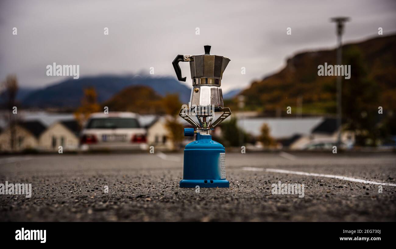 Faire un café ou un thé - cafetière pendant un randonnée pédestre ou camping avec un poêle à gaz de camping - dans un parking avec un fjord norvégien dans le arrière-plan Banque D'Images