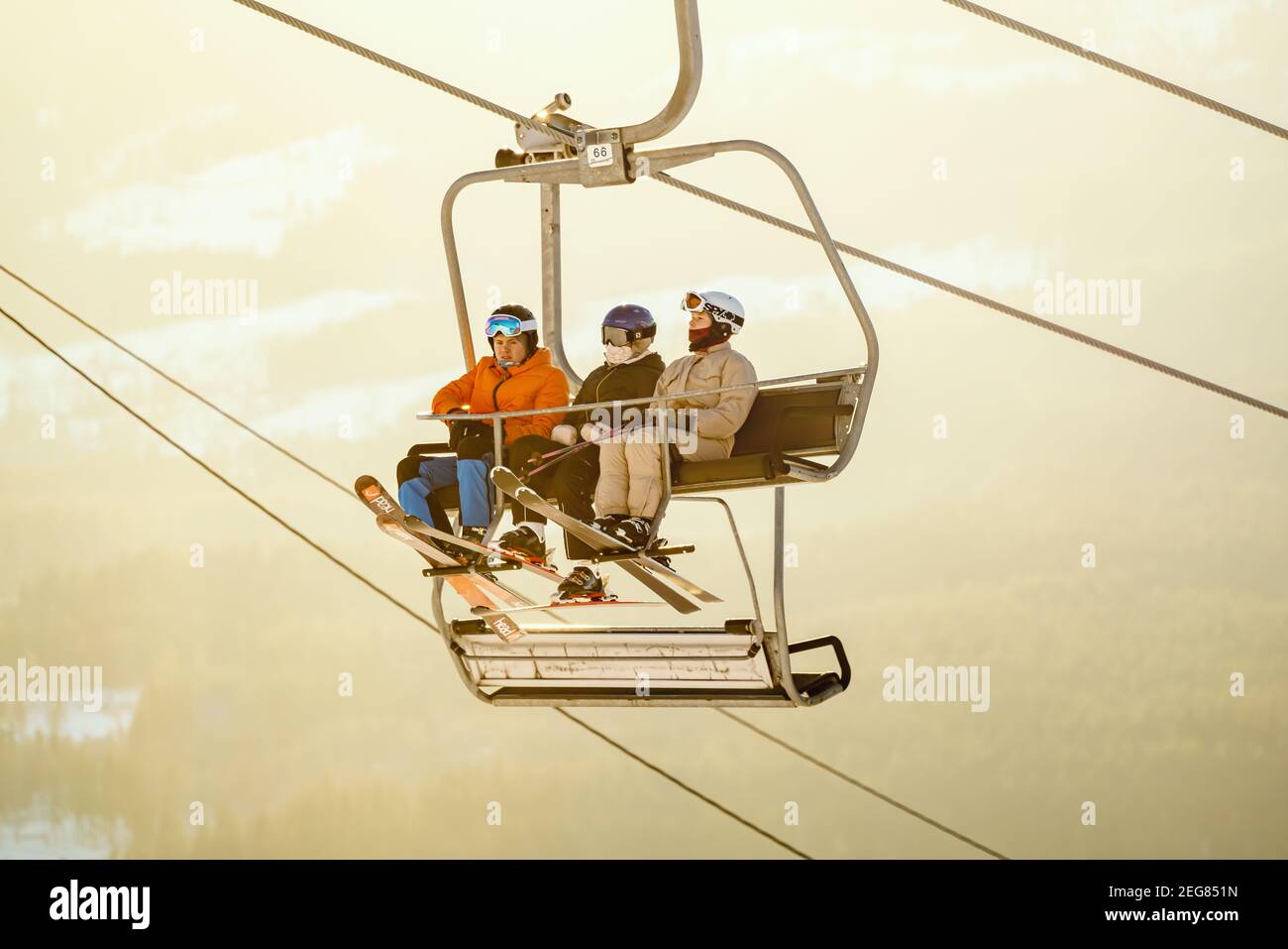 Groupe d'adolescents skiant sur un télésiège dans la lumière chaude du soir. Banque D'Images