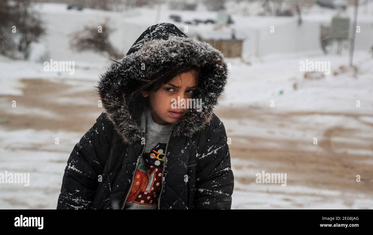 Pauvre portrait de fille de réfugié syrien regardant l'appareil photo dans Neige Météo après blizzard dans le camp de refuge de la Syrie libanaise Bordures Banque D'Images
