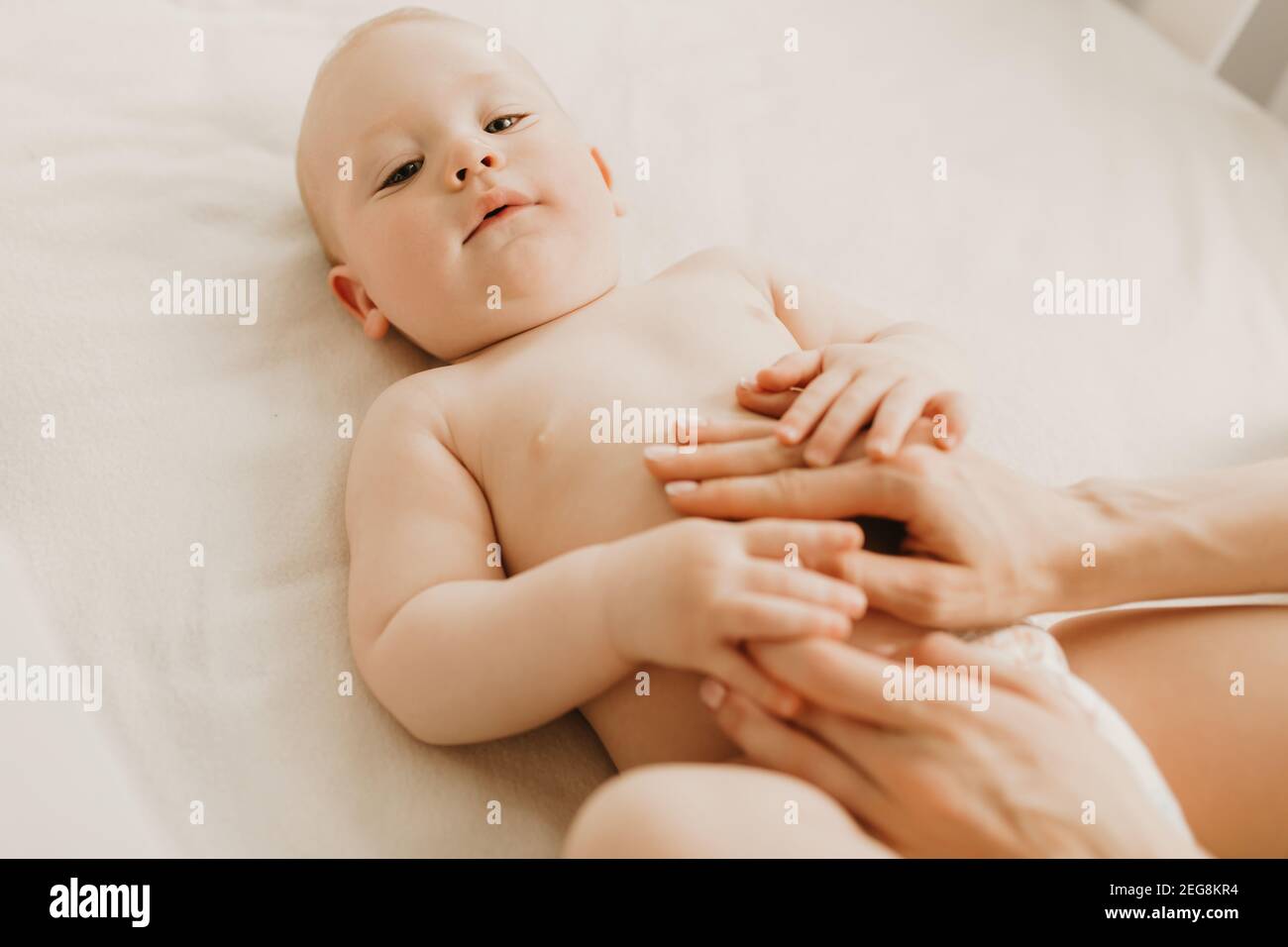 Massage De Bebe Maman Massage Le Ventre De Bebe Pendant La Colique Nouveau Ne Avec Colique Couche Sur Son Dos Sans Vetements La Main De Mere Sur Son Ventre L Aide Photo Stock