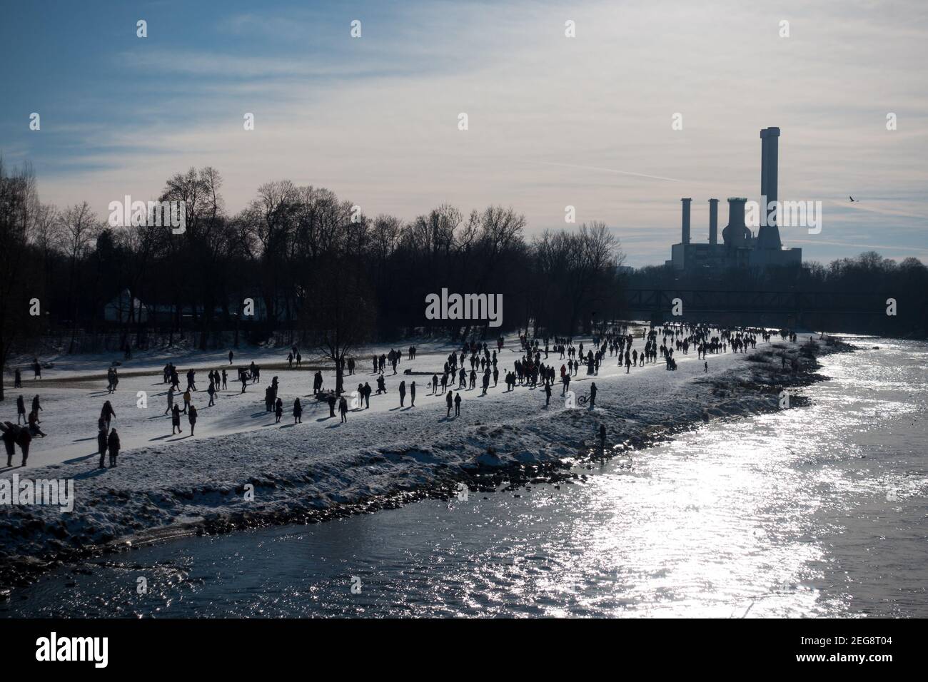 Les personnes marchant le long de la rivière Isar côté eau en profitant de la journée ensoleillée dehors. Une station d'alimentation est visible en arrière-plan. Banque D'Images