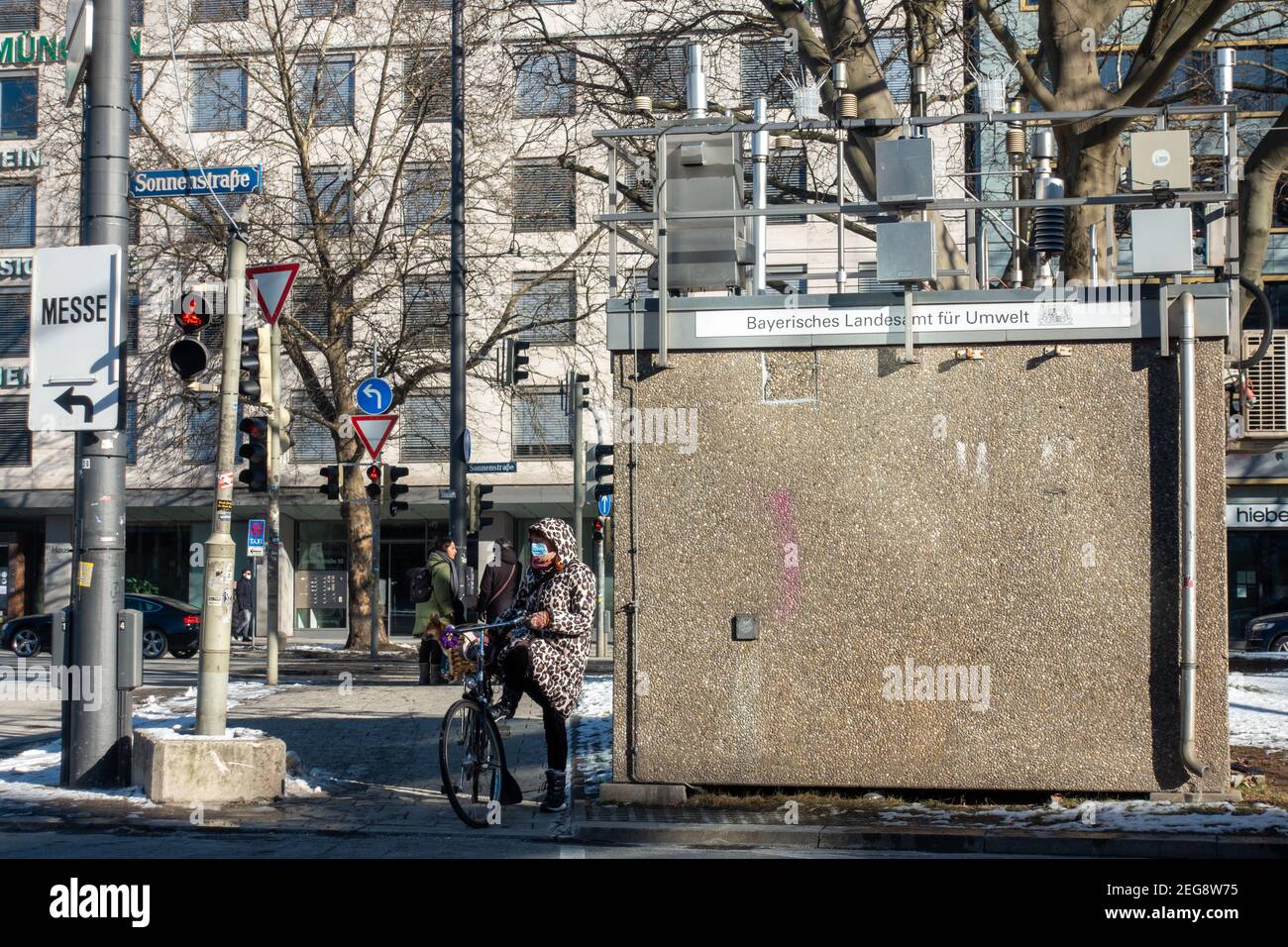 Munich, Allemagne - 13 février 2021 : une femme à vélo attend le feu vert pour aller dans la rue principale de la ville Banque D'Images Munich, Allemagne - 13 février 2021 : une femme à vélo attend le feu vert pour aller dans la rue principale de la ville Banque D'Images