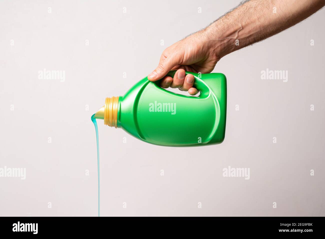 Verser le détergent liquide de la bouteille verte devant un fond gris clair, modèle de série maquette modifiable prêt pour votre conception, sélection d'étiquettes Banque D'Images