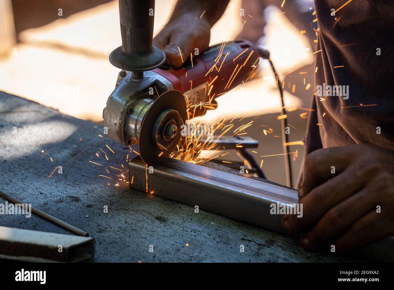 un homme qui coupe une barre métallique avec un électrique circulaire outil  qui produit des étincelles Photo Stock - Alamy