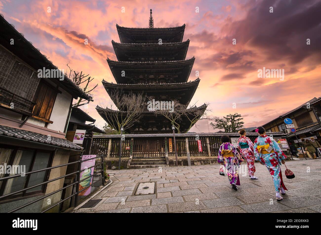 Trois femmes portant un kimono marchent devant le temple Kiyomizu-dera pendant un coucher de soleil époustouflant. Kyoto, Japon. Banque D'Images