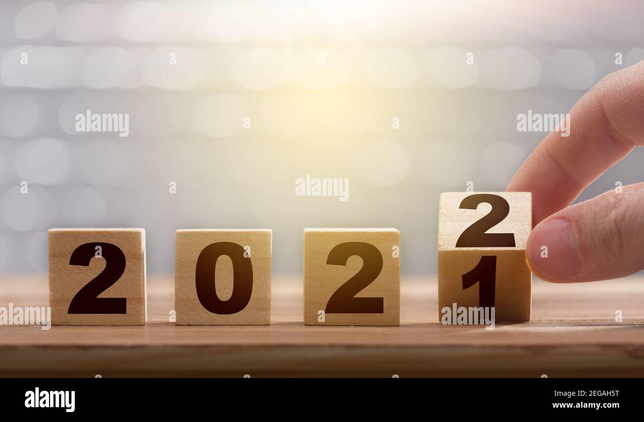 Doigts tournant le bloc de 2021 à 2022. Concept de la nouvelle année. Chiffres de l'année 2022 sur un bloc de bois Banque D'Images