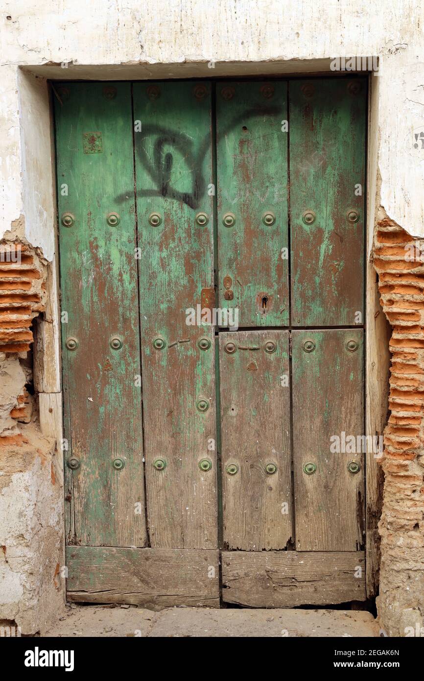 Vieille porte vieillissante - patina défraîchi d'une porte cloutée en bois vert avec graffiti. L'une d'une série. Aspect abîmé. Entrée d'un logement en Espagne. Banque D'Images