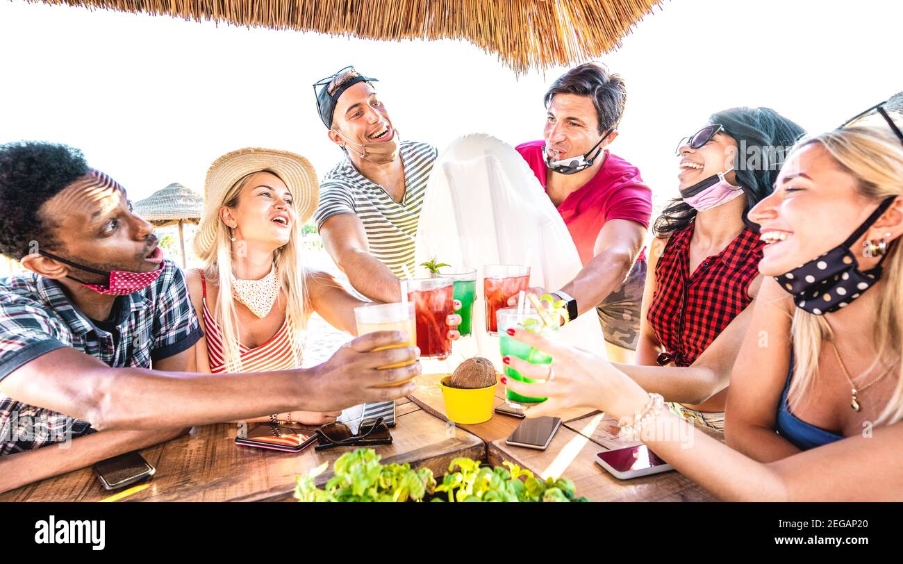 De jeunes amis multiraciaux boivent au bar à cocktails de la plage avec ouvert Masque de visage - Nouveau concept d'été normal avec les milenials ayant amusez-vous ensemble Banque D'Images