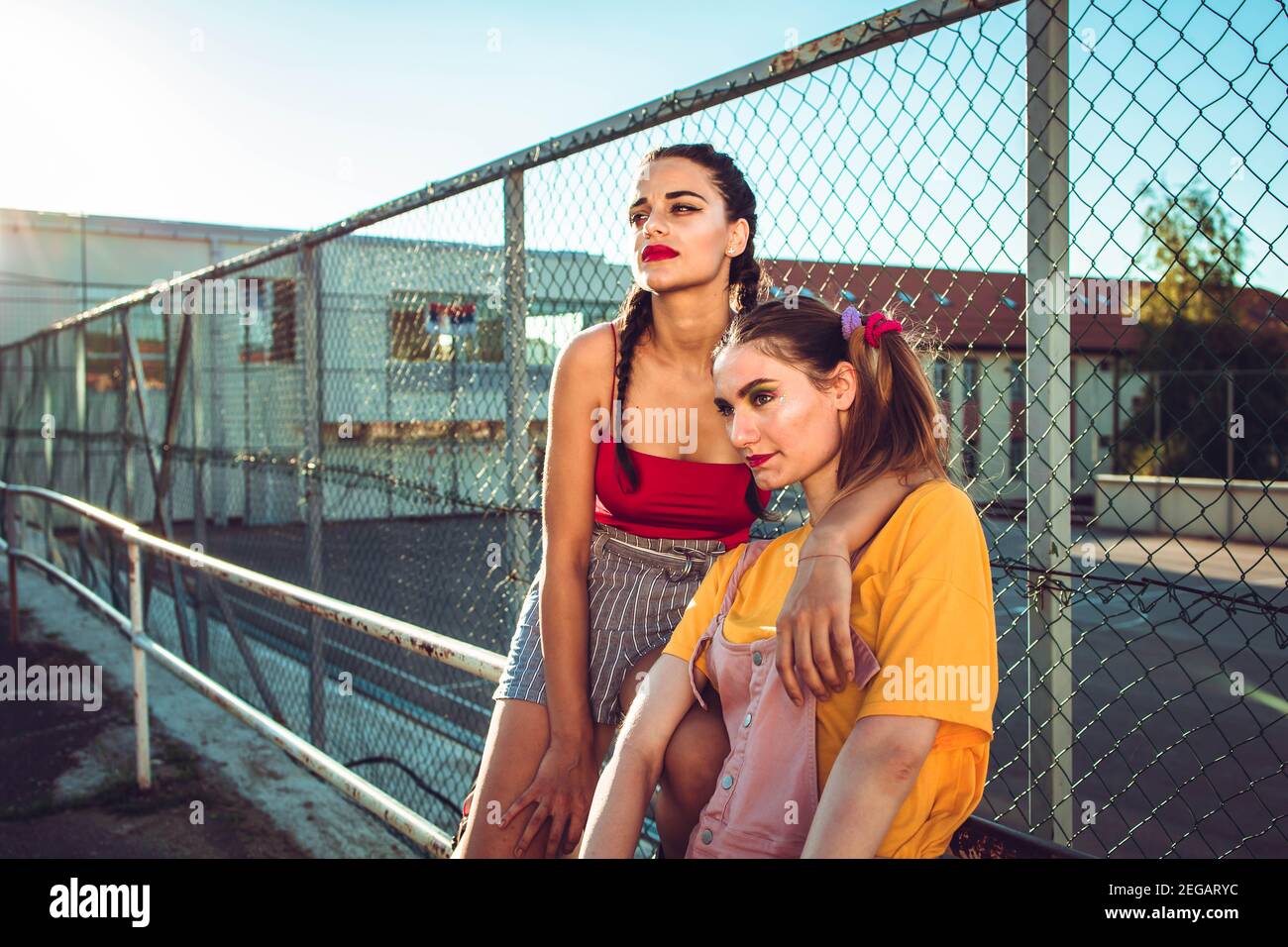 Deux filles adolescentes, amis en vêtements colorés avec patins à roulettes et câlins de planche à roulettes. Style urbain Banque D'Images