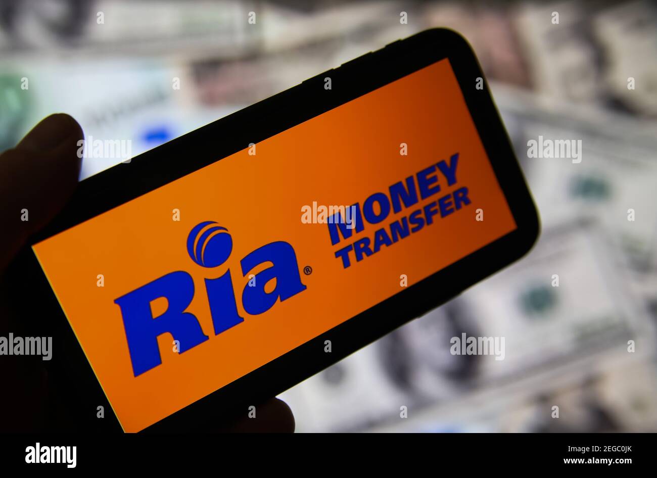 Viersen, Allemagne - février 9. 2020: Gros plan de l'écran de smartphone avec logo lettrage du service de transfert d'argent en ligne ria, billets flous backgrou Banque D'Images