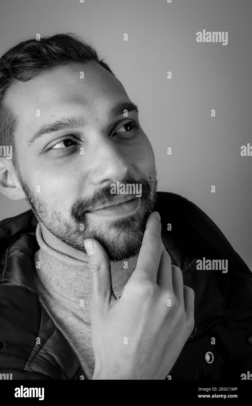 Portrait noir et blanc d'un jeune homme touchant le sien menton dans un moment d'inspiration Banque D'Images