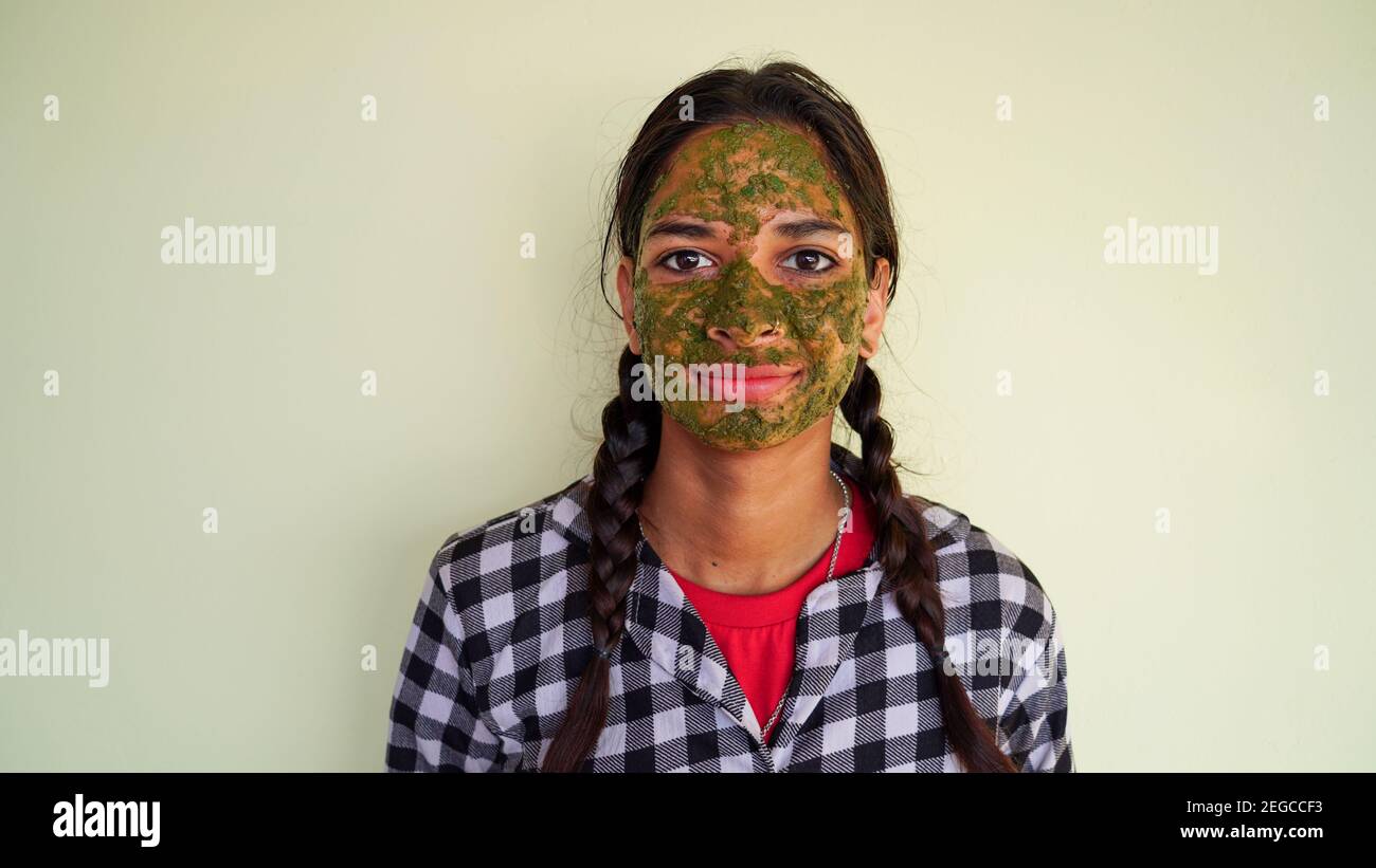 Portrait d'une fille indienne avec des paquets verts de visage ayurvédique isolés sur fond blanc. Femmes utilisant le masque facial Rose et Neem pour le visage brillant Banque D'Images