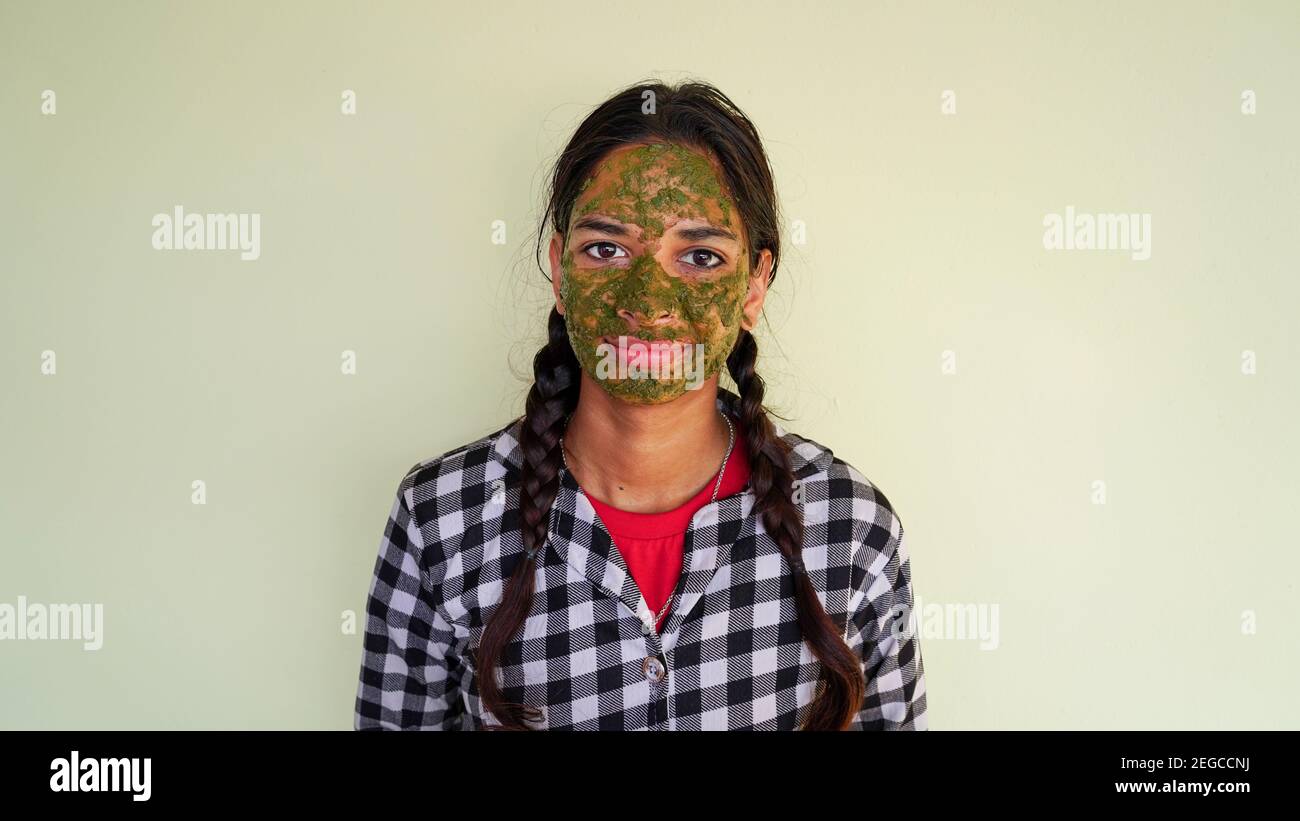Portrait d'une fille indienne avec des paquets verts de visage ayurvédique isolés sur fond blanc. Femmes utilisant le masque facial Rose et Neem pour le visage brillant Banque D'Images