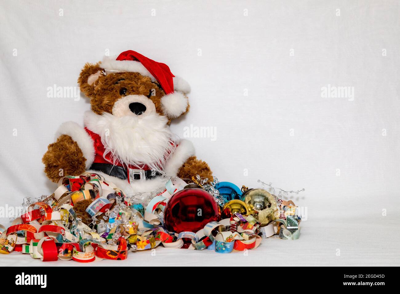 Ours en peluche de Noël dans une tenue de père Noël emmêlée d'un arrière-plan blanc de la chaîne de papier avec espace de copie Banque D'Images