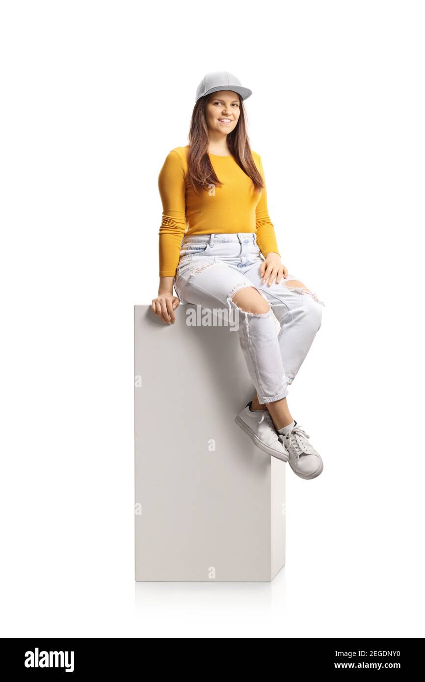 Jeune femme assise sur une colonne blanche et souriante caméra isolée sur fond blanc Banque D'Images