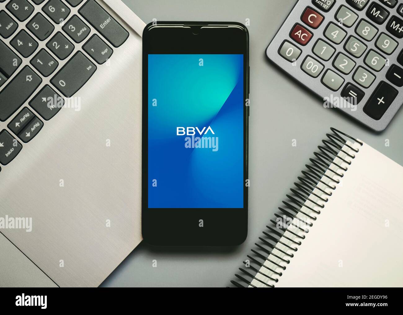 Logo de l'application mobile BBVA sur l'écran du smartphone, à côté d'un ordinateur portable, d'un ordinateur portable et d'une calculatrice, sur fond gris Banque D'Images