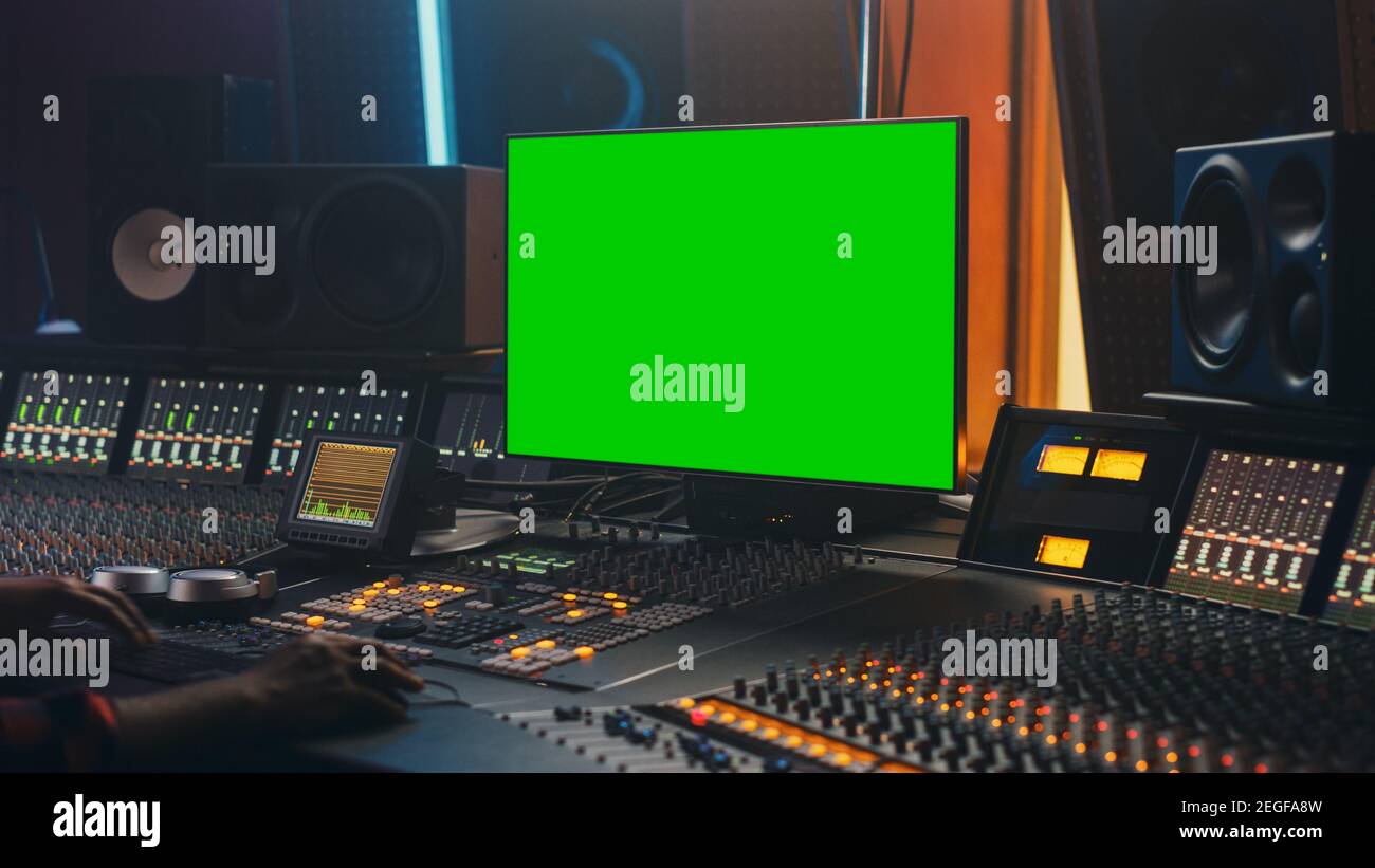 Portrait d'un ingénieur audio élégant travaillant dans Music Record Studio, utilise un ordinateur à écran vert, un tableau de mixage, un bureau de contrôle pour créer un nouveau morceau. Au-dessus de Banque D'Images