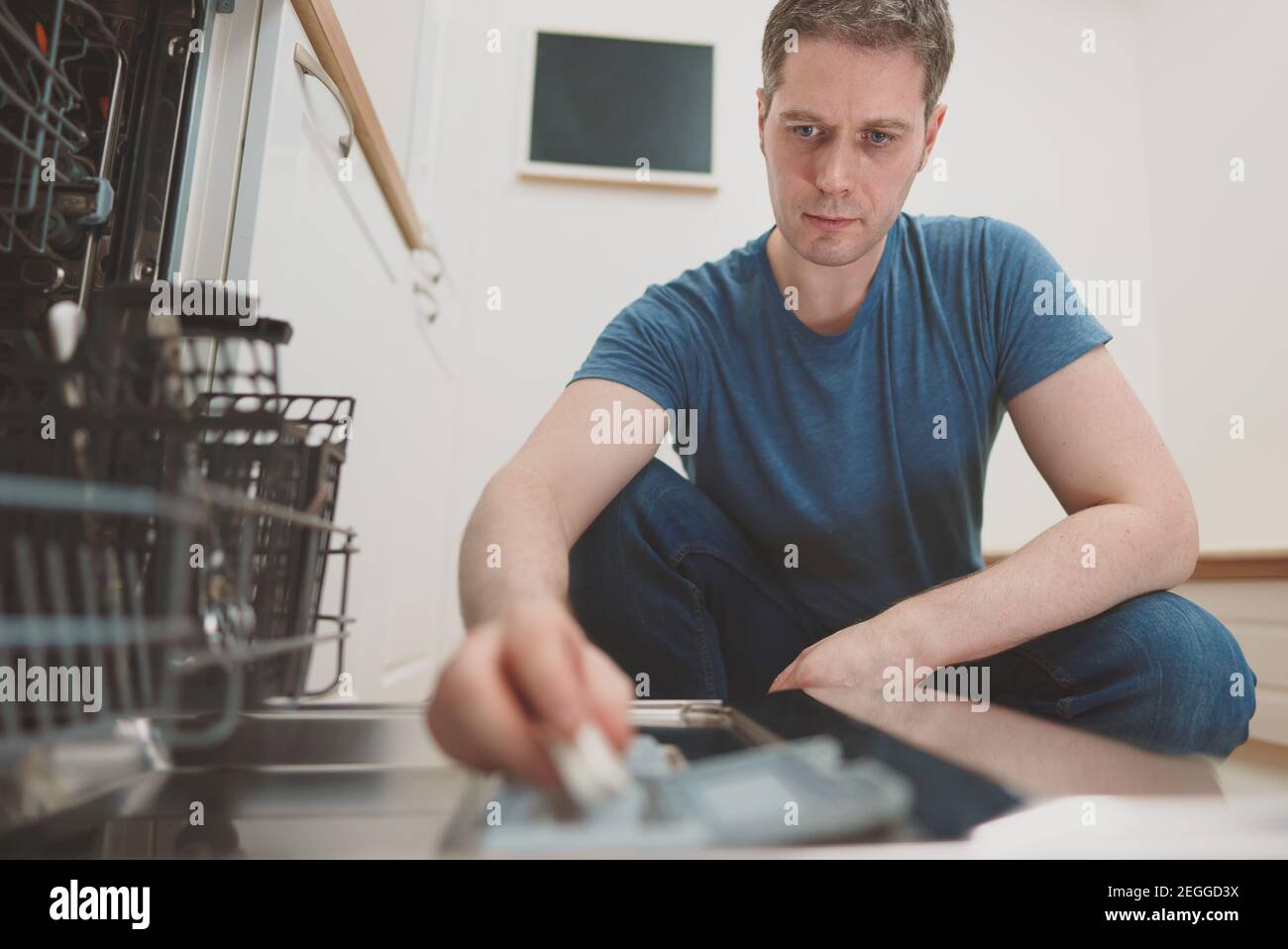 Homme mettant la tablette de détergent au lave-vaisselle. Banque D'Images