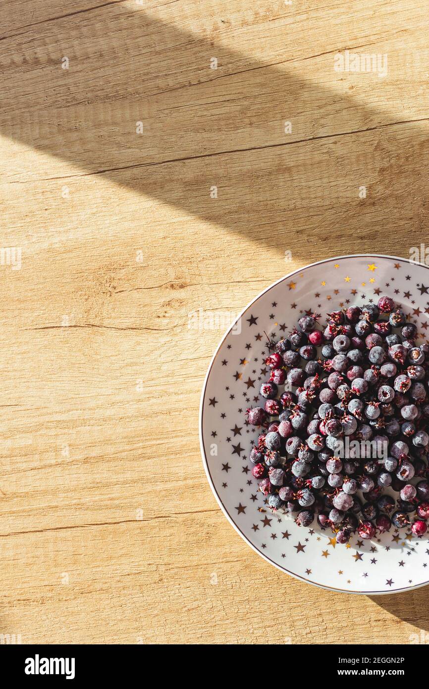 Baies congelées sur une assiette vue sur un fond en bois. Modèle pour le menu Banque D'Images