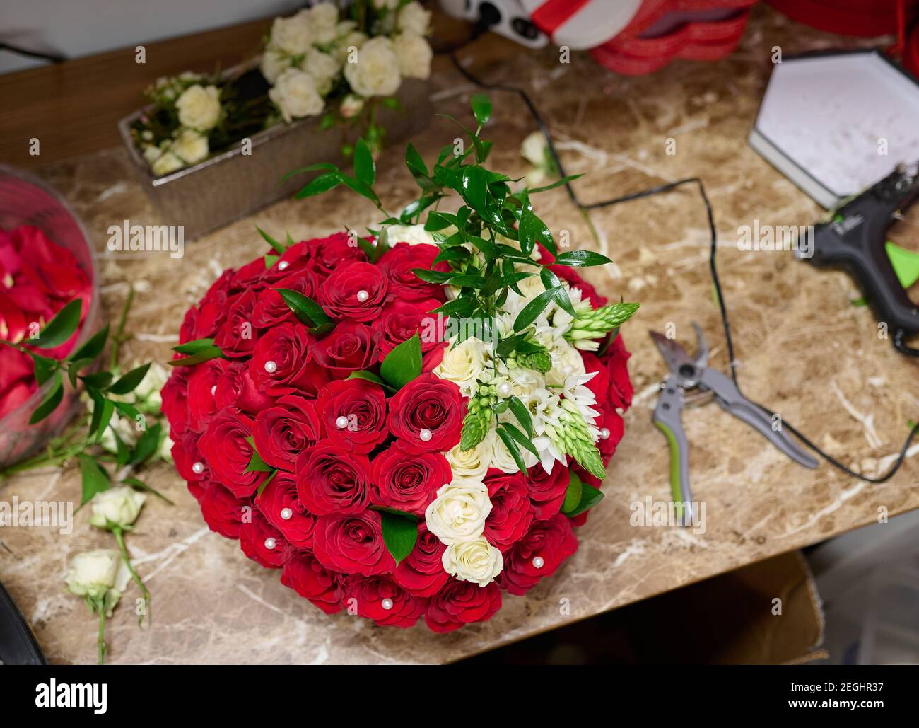 Boîte à fleurs avec roses rouges et fleurs blanches sur la table, processus d'assemblage de boîte à fleurs Banque D'Images