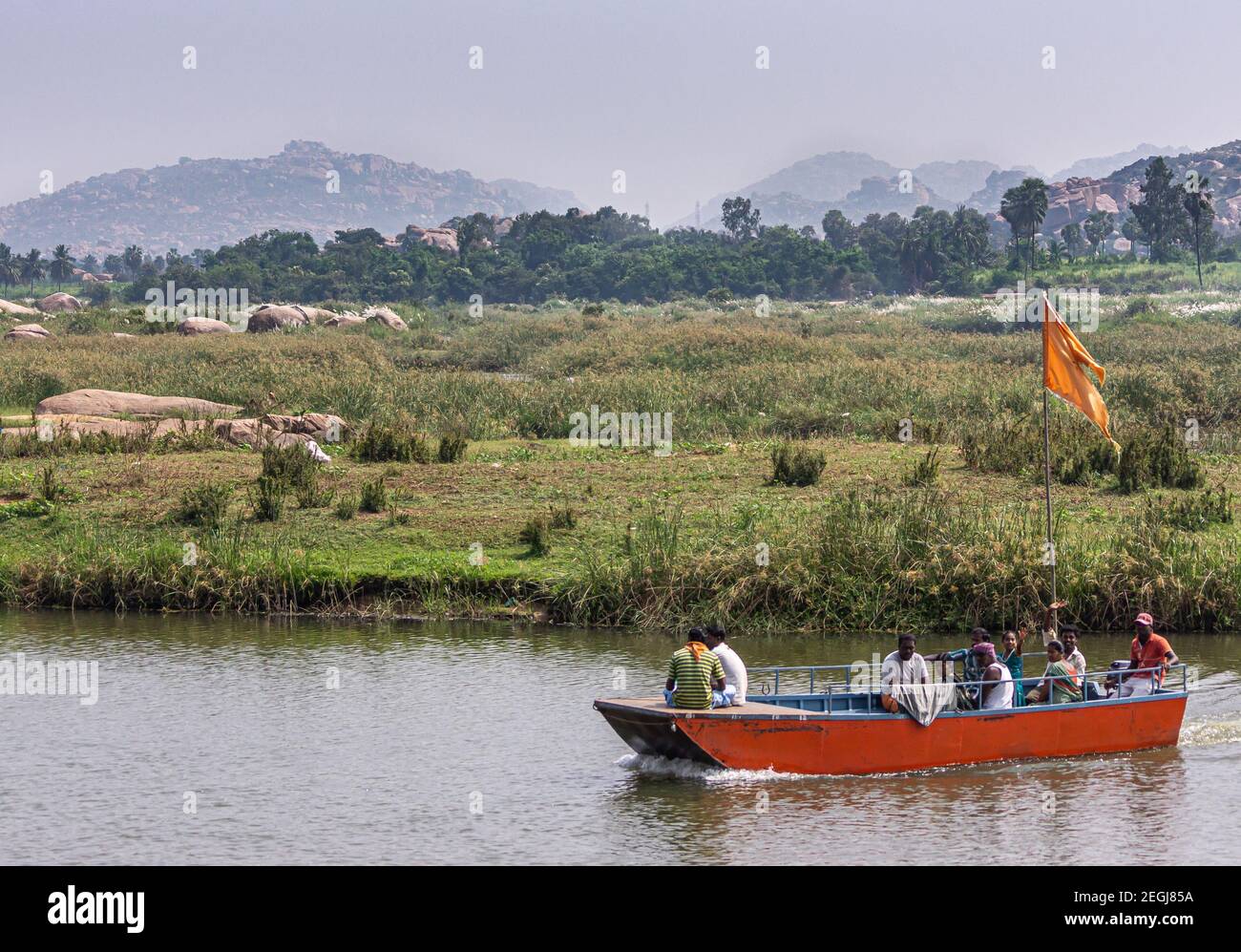 Anegundi, Karnataka, Inde - 9 novembre 2013 : petit traversier rouge sur la rivière Tungabhadra entre les îles du temple et la terre principale. Beaucoup de Mars vert Banque D'Images