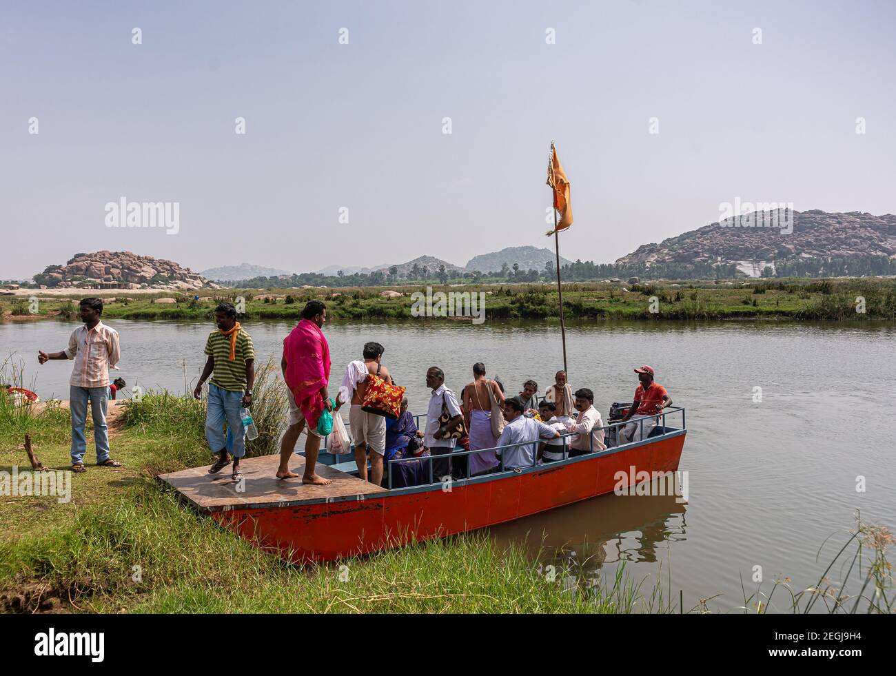 Anegundi, Karnataka, Inde - 9 novembre 2013 : petit traversier rouge sur la rivière Tungabhadra entre les îles du temple et la terre principale pleine de personnes prêtes Banque D'Images