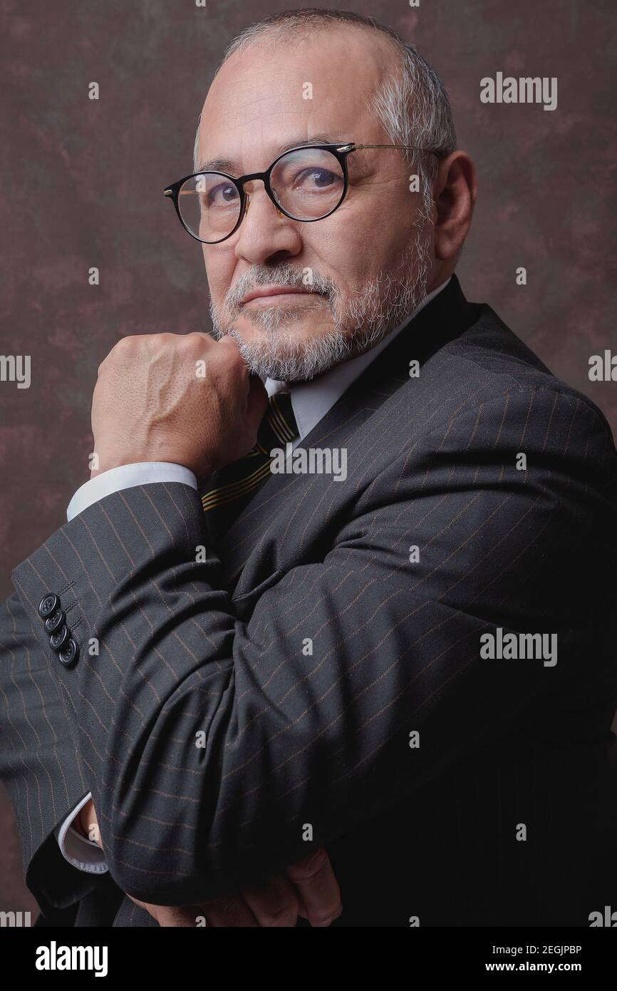 Un homme mûr posant pour la caméra dans une obscurité costume et chapeau à fines rayures marron Banque D'Images