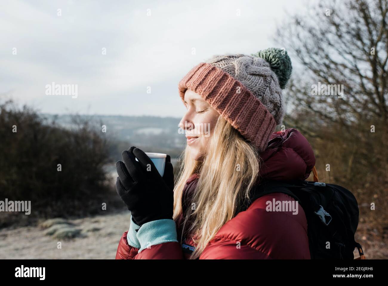 femme souriante tenant une boisson chaude tout en appréciant le froid Air au Royaume-Uni Banque D'Images