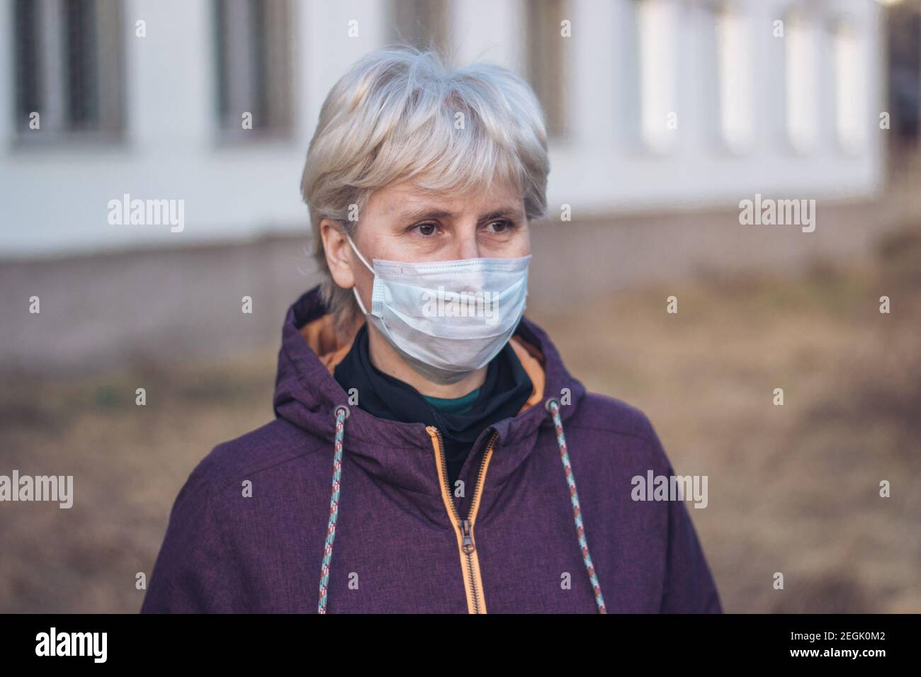 Portrait d'une femme d'âge moyen, triste et pensive, debout dans la rue et portant un masque respiratoire pour protéger sa santé. Gros plan. Concept de protection. Banque D'Images