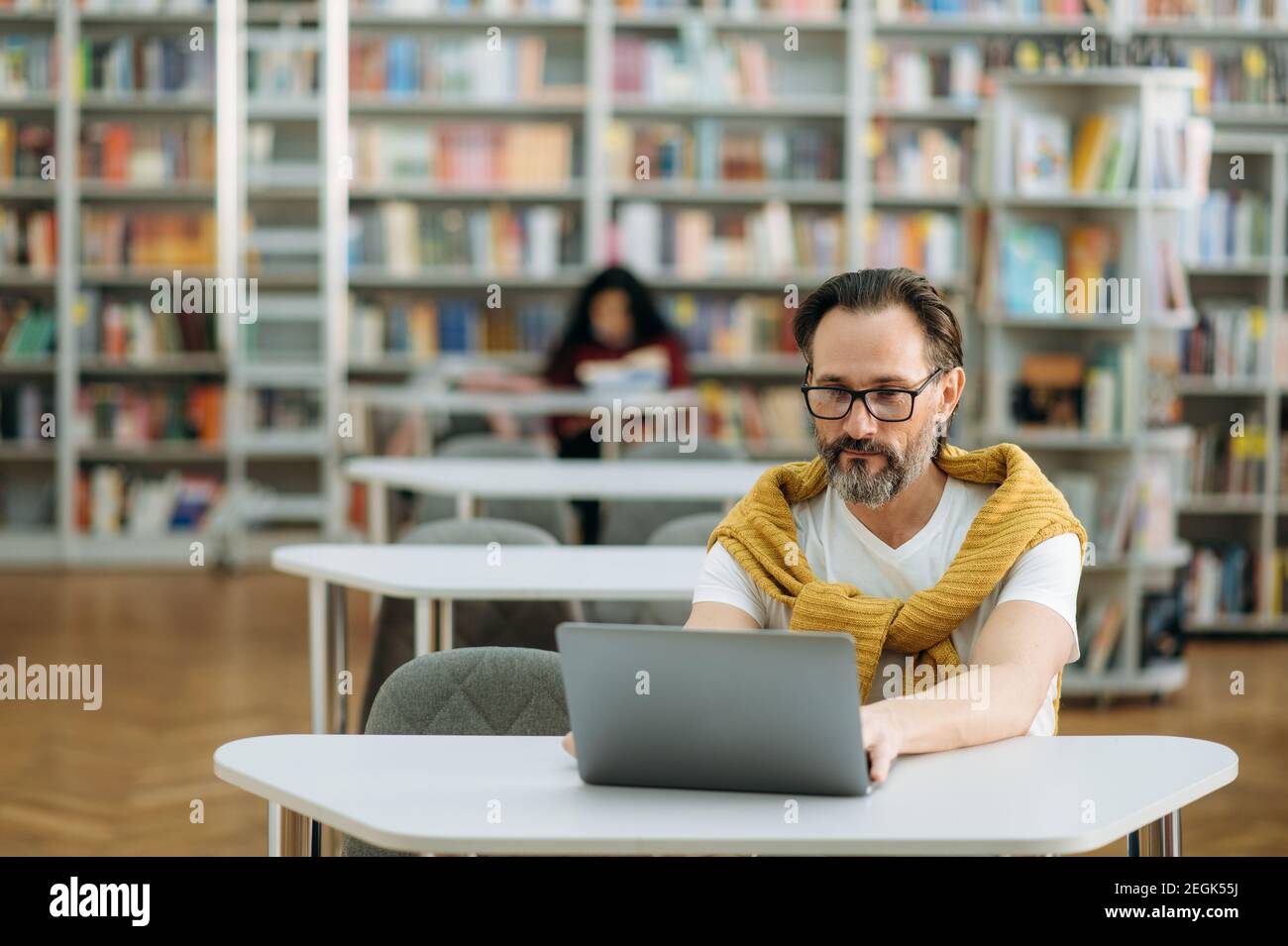 Un travailleur indépendant concentré est assis au bureau, utilise un ordinateur portable, développe un nouveau projet. L'homme moderne senior travaille sur un nouveau plan d'affaires pour l'entreprise, à la recherche d'idées Banque D'Images