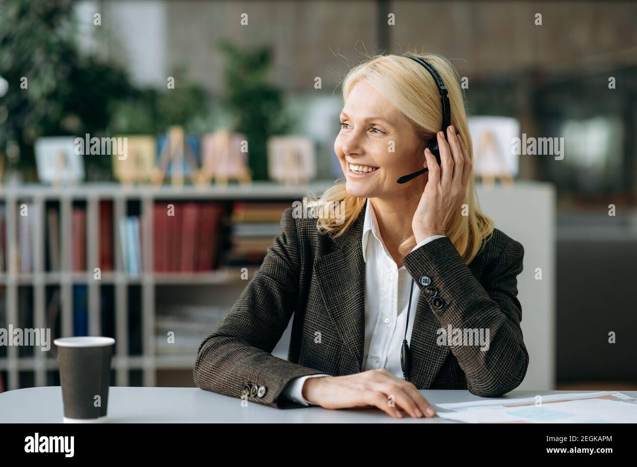 Portrait d'une élégante femme d'âge moyen en costume et casque formels. Femme d'affaires caucasienne travaille dans le centre de soutien, communiquant avec les clients, concept de centre d'appel Banque D'Images