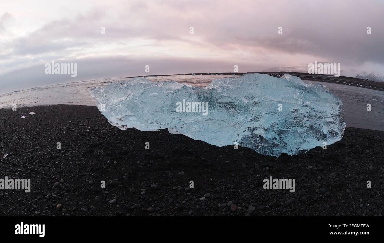 Le grand iceberg scintille sur le sable noir à Diamond Beach Islande Banque D'Images