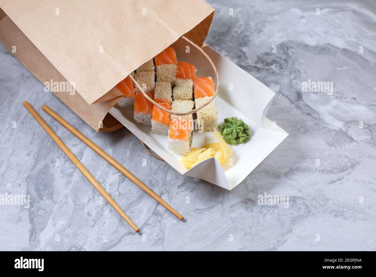 Boîte à emporter avec petits pains à sushis dans un sac en papier brun. Concept sushi To Go. Banque D'Images