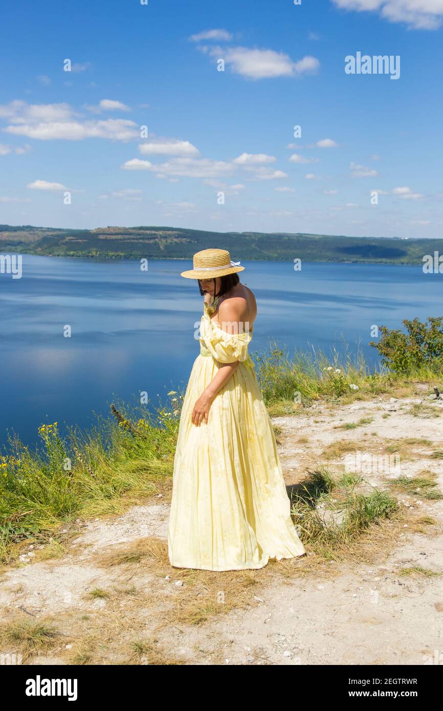 Une fille dans une longue robe debout sur une falaise par la baie Banque D'Images