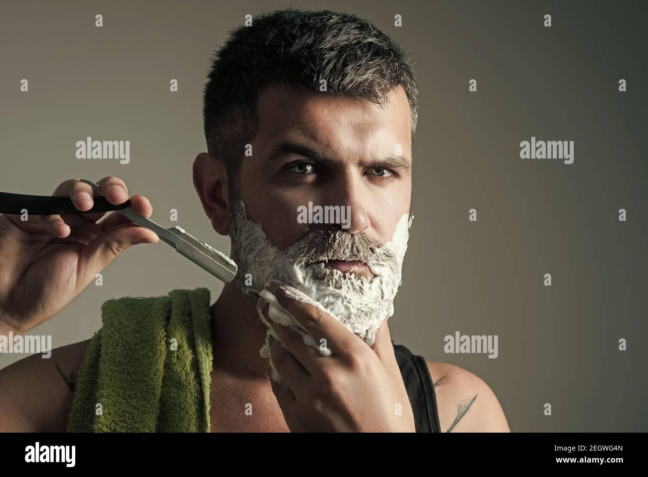 Hipster dans un salon de coiffure. L'homme a coupé la barbe et la moustache  avec un rasoir et une brosse à rasage. Coupe de cheveux d'homme barbu.  Salon de coiffure. Mode et
