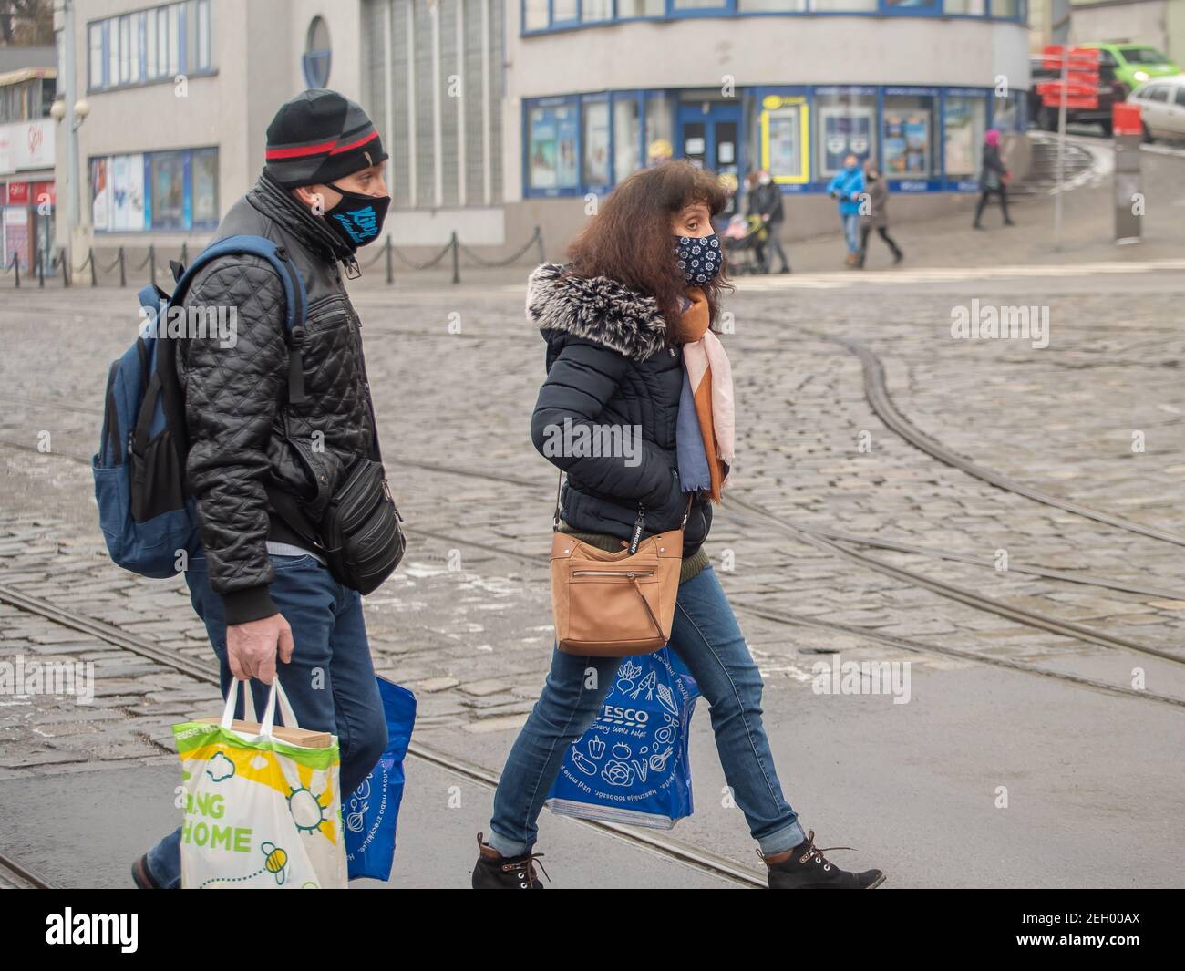 Brno, République tchèque. 02-17-2021. Homme et femme migrants avec masque pour protéger contre le virus corona marcher sur la station de tramway principale de Halvni Nadrazi dans le c Banque D'Images