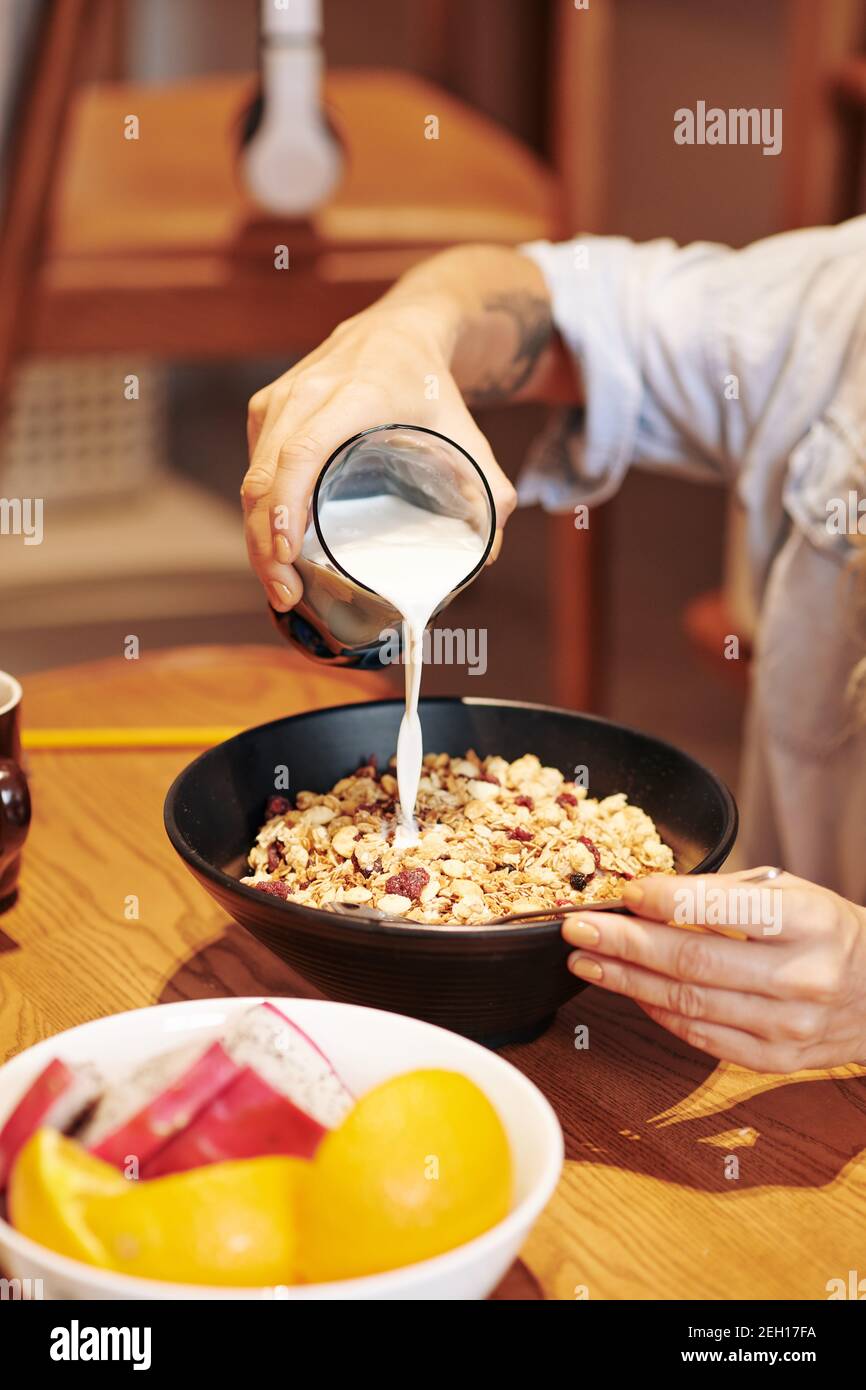 Verser le lait dans un bol de muesli Banque D'Images