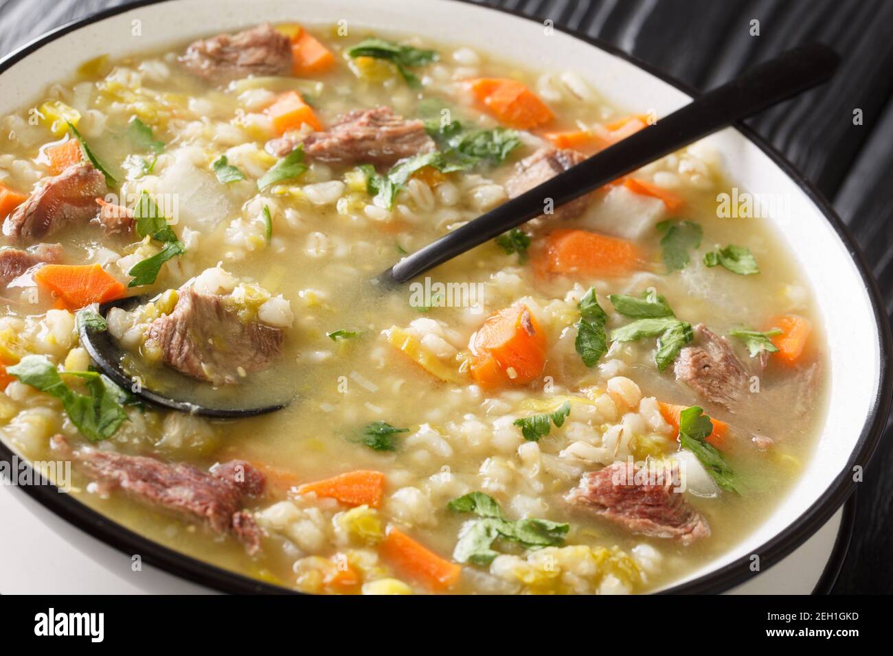 Savoureux bouillon Scotch Rich rempli de morceaux de légumes de la taille d'une morsure et d'agneau tendre dans l'assiette sur la table. Horizontale Banque D'Images