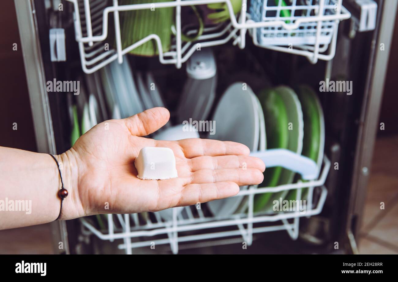Mise au point sélective sur la main de femme, en tenant la dosette naturelle maison pour lave-vaisselle, pour une mise au point automatique de la vaisselle sur l'arrière-plan. Concept de mode de vie écologique et durable Banque D'Images