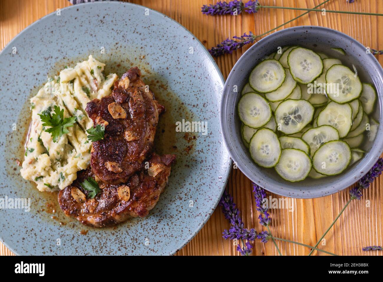 Encolure de porc cuite avec purée de pommes de terre et persil, bacon rôti et salade de concombres. Banque D'Images