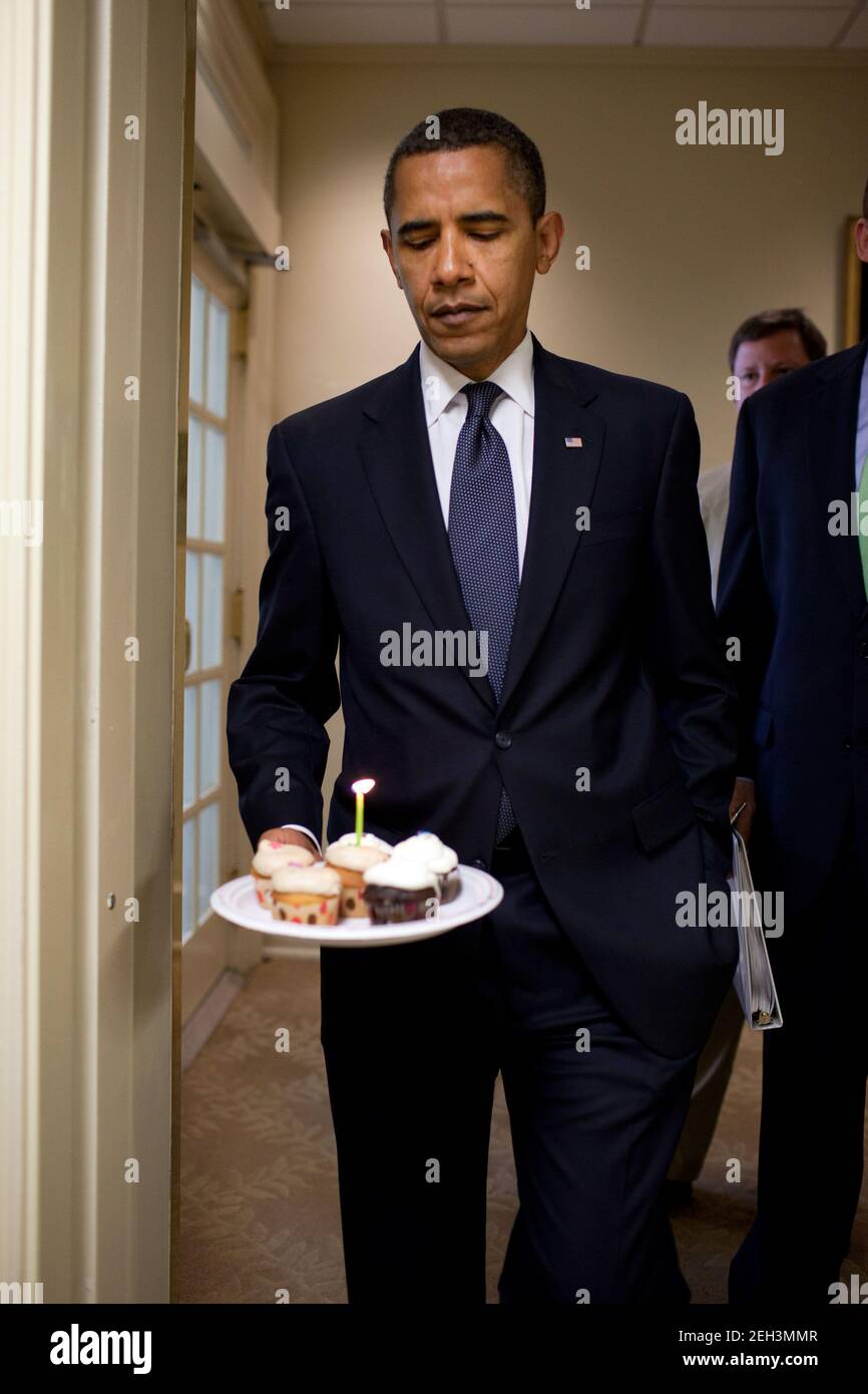 Le président Barack Obama observe la flamme sur la bougie lorsqu'il se rend à la Brady Briefing Room pour présenter des cupcakes à Helen Thomas, chroniqueur à la Maison-Blanche de Hearst, en l'honneur de son anniversaire, le 4 août 2009. Thomas, qui a 89 ans, partage le même anniversaire qu'Obama, qui a 48 ans. Banque D'Images