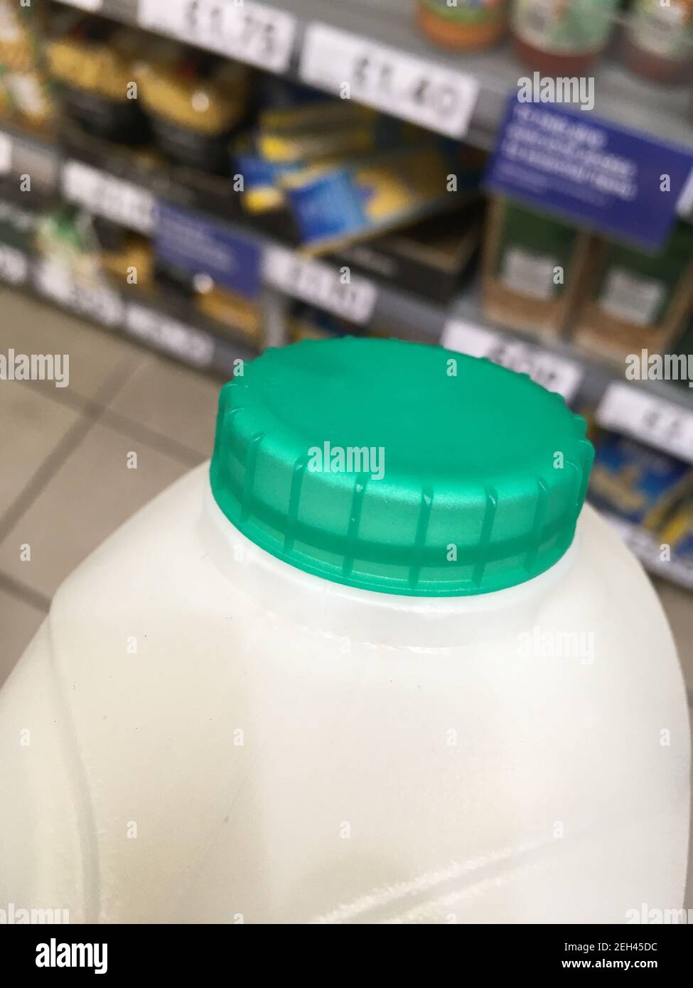 Un carton de lait pasteurisé demi-écrémé britannique avec un dessus de bouteille vert transporté d'une étagère à la caisse dans un supermarché. Le client achète le lait à la boutique. ROYAUME-UNI. (123) Banque D'Images