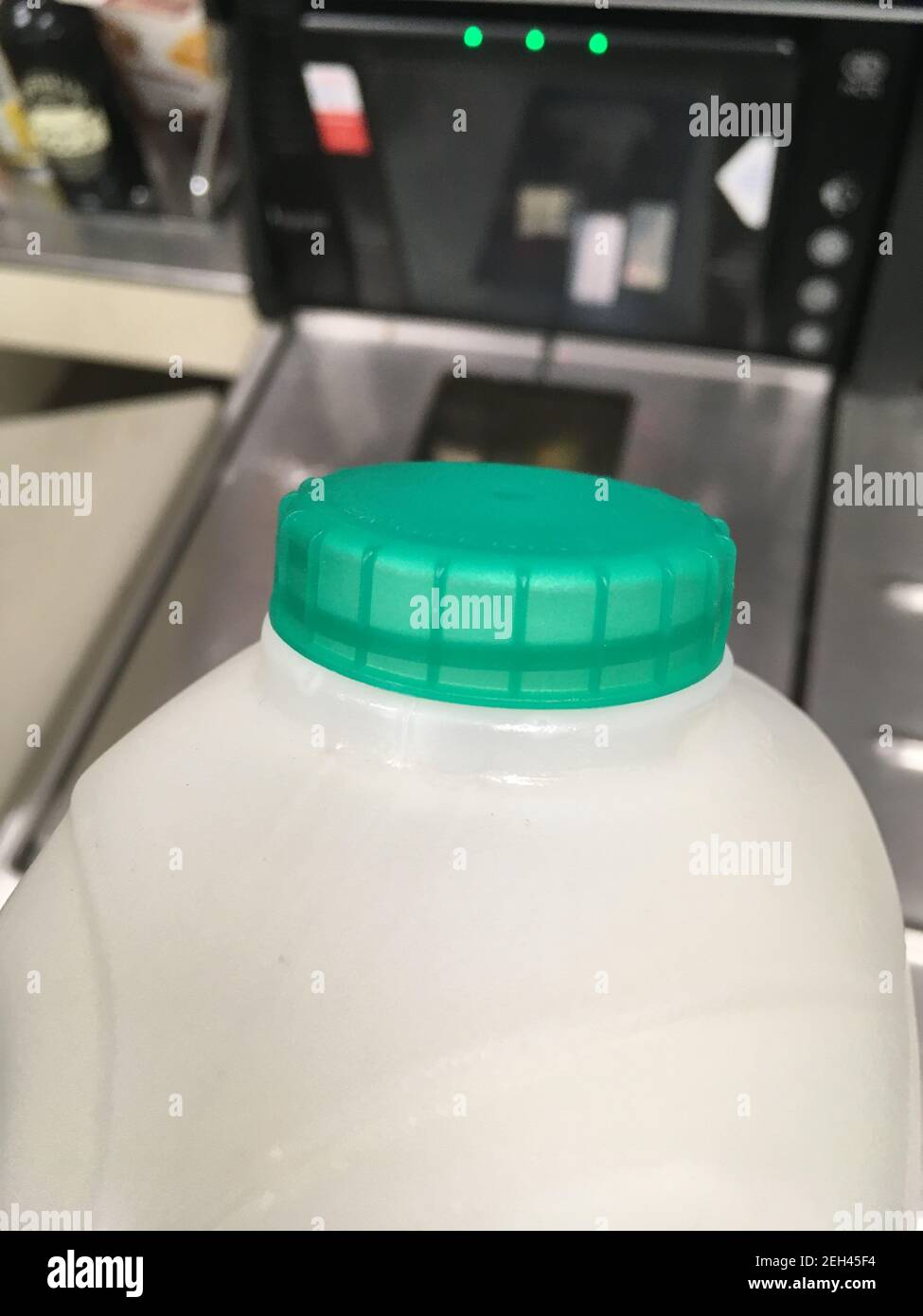 Un carton de lait pasteurisé demi-écrémé britannique avec un dessus de bouteille vert transporté d'une étagère à la caisse dans un supermarché. Le client achète le lait à l'atelier et le scanne à la caisse libre-service. Un petit achat avec une carte de crédit; sont les gens utilisent le paiement par carte pour de très petits montants en raison de verrouillage et sans argent à venir normal. ROYAUME-UNI. (123) Banque D'Images