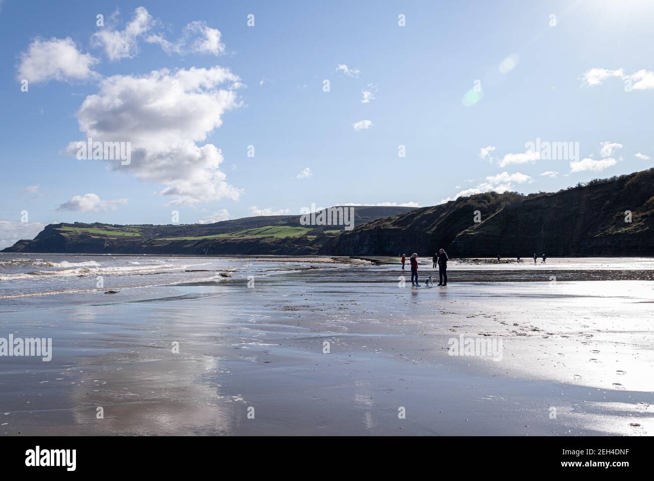 Vacanciers sur la plage à marée basse au soleil, Robin Hood Bay, Yorkshire, Angleterre Banque D'Images