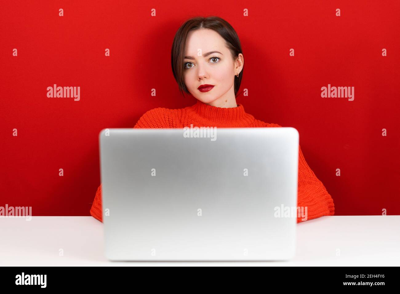 belle fille à l'ordinateur sur un fond rouge Banque D'Images