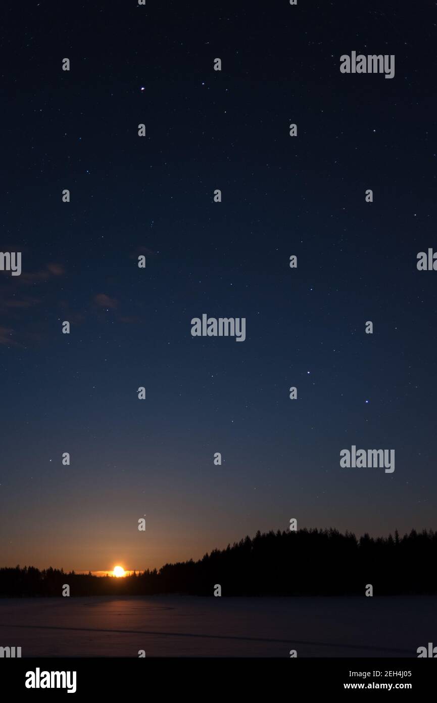 La lune s'élève au-dessus du paysage d'hiver la nuit Banque D'Images