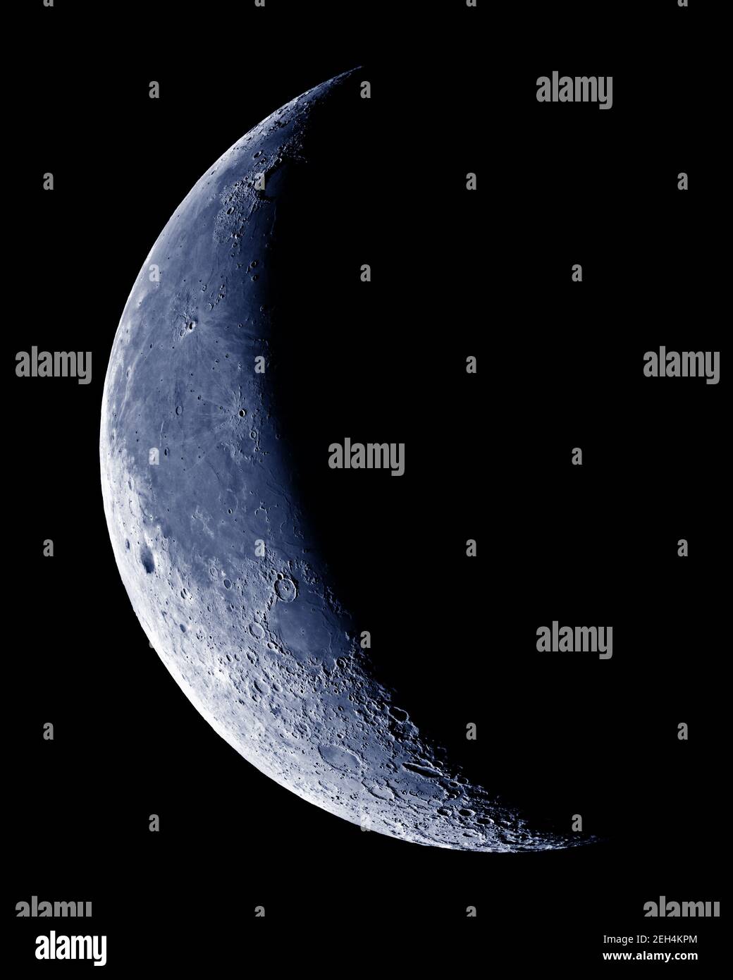 Lune en croissant avec détail cratère sur ciel bleu. Banque D'Images