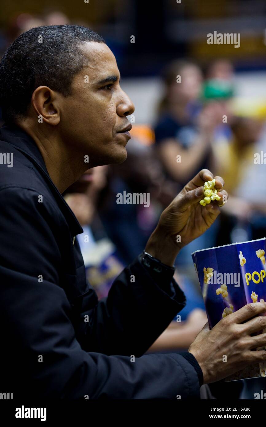 Le président Barack Obama mange du pop-corn tout en regardant un match de basketball universitaire entre l'État de l'Oregon, qui est entraîné par son beau-frère Craig Robinson, et l'université George Washington à Washington, D.C., le 28 novembre 2009. Banque D'Images